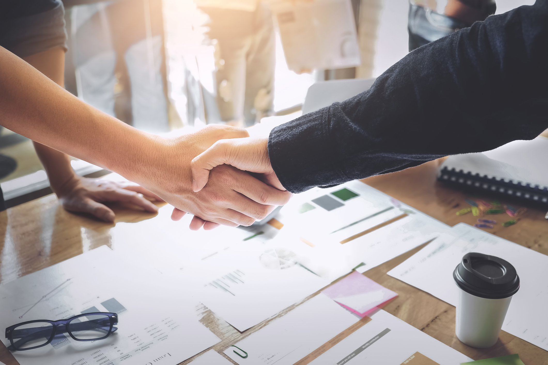 Handshake over a table strewn with contracts