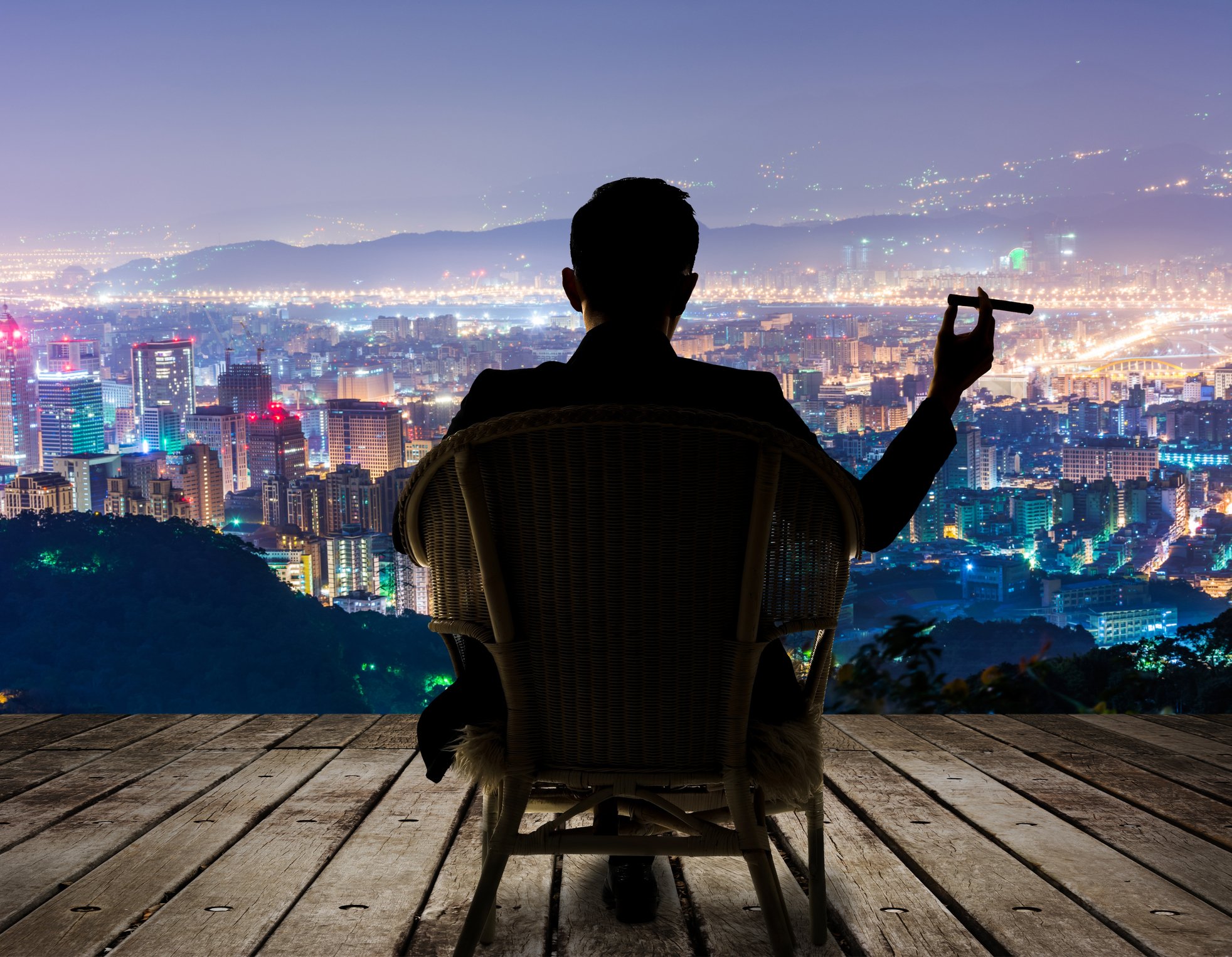 Man in chair with cigar, looking down on 20+ commercial properties