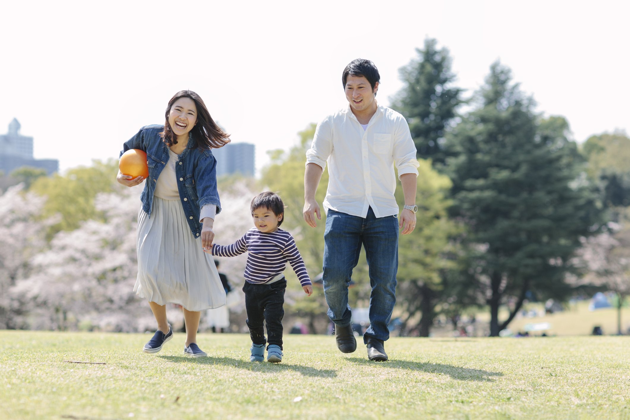 A couple with a young child playing around in the park