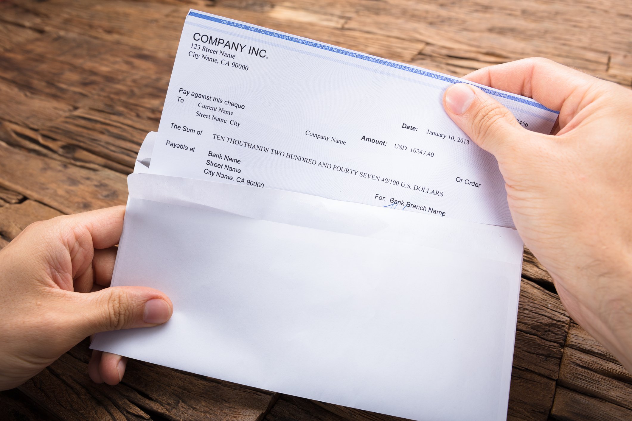 Someone taking a paycheque out of an envelope