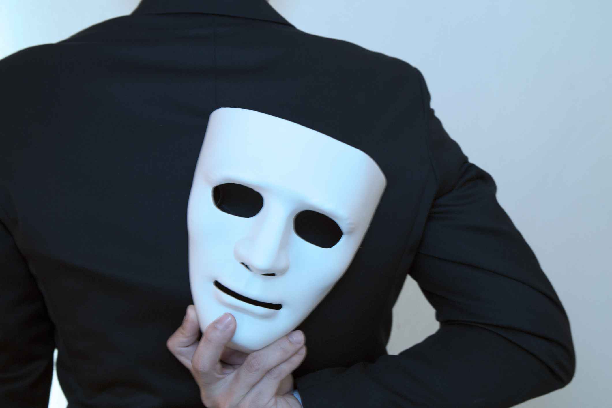 Man holds a mask behind his back