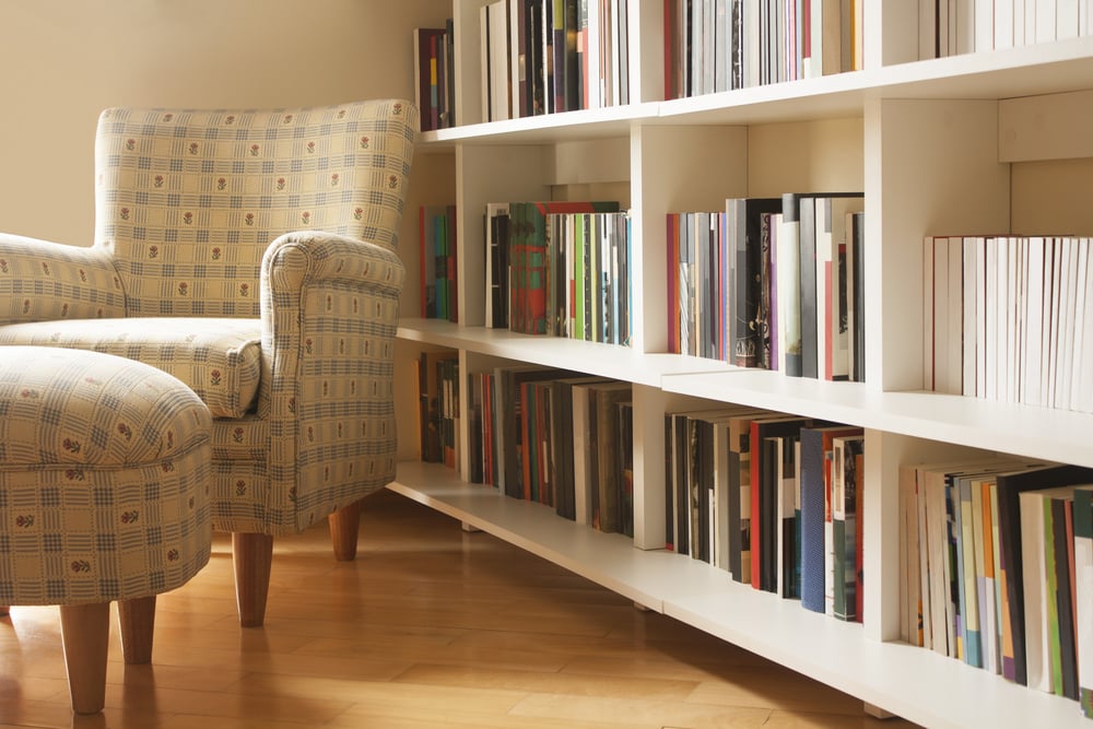 room with books on shelves and armchair