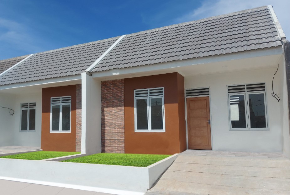 Rumah subsidi tipe minimalis dengan cat cokelat dan putih, atap genteng abu-abu, serta halaman kecil depan rumah
