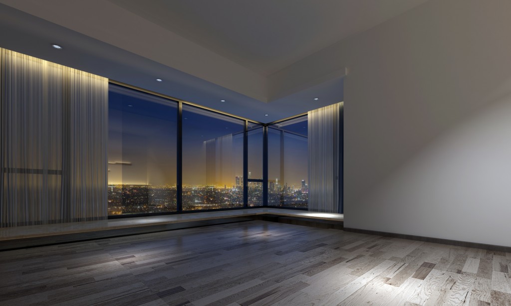 Dimly lit empty room facing urban skyline