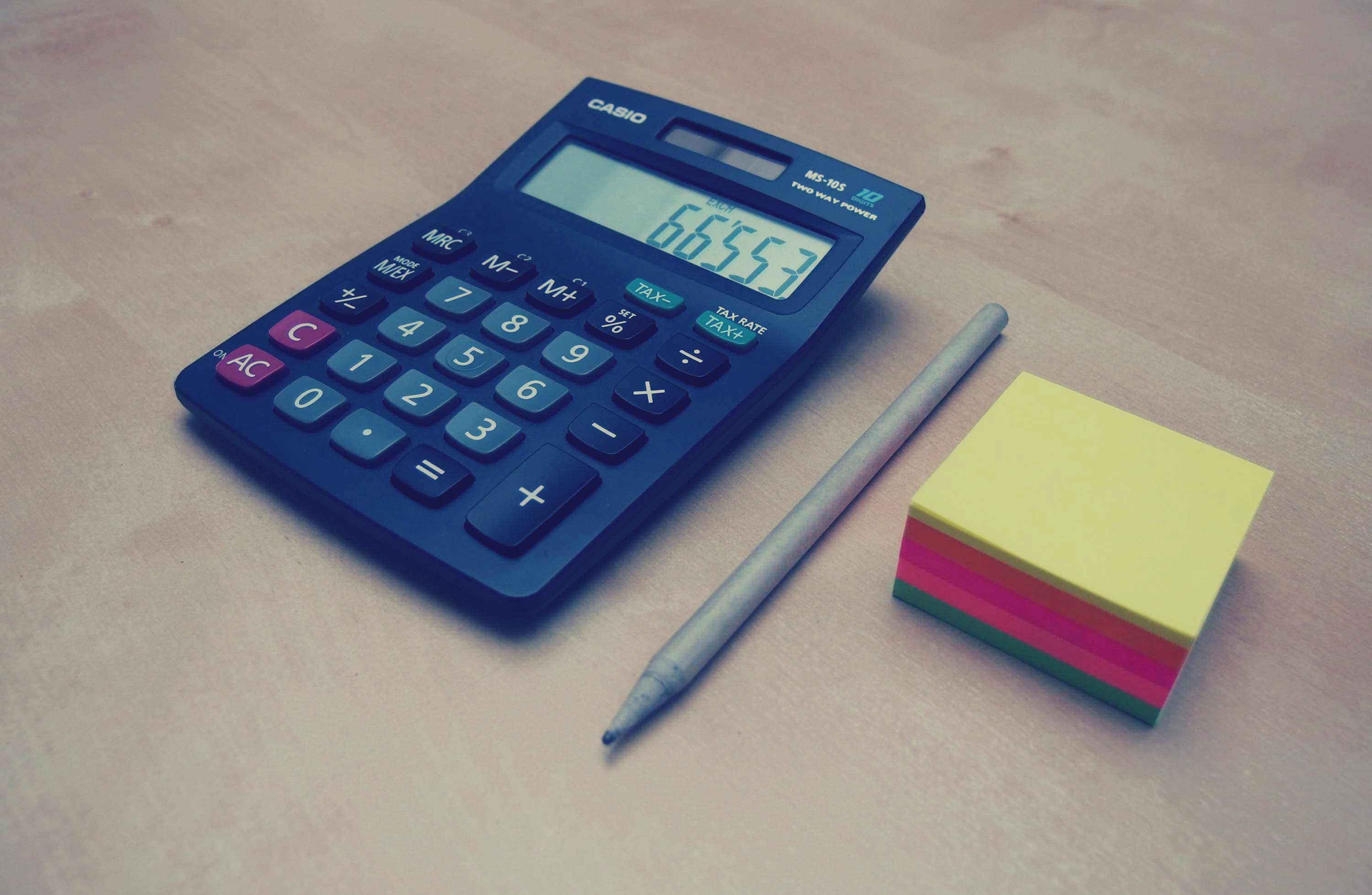 a calculator, pen, and sticky notes