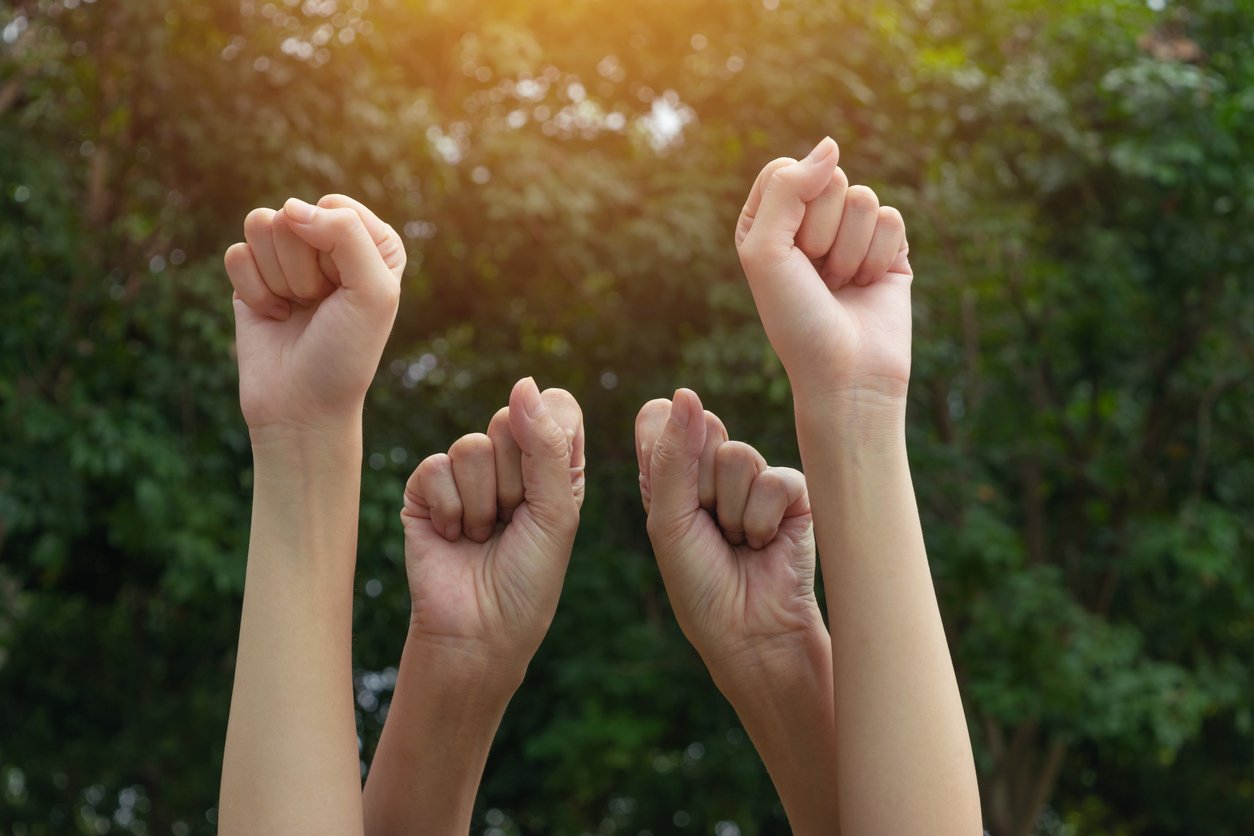 Four clenched hands up in the air.
