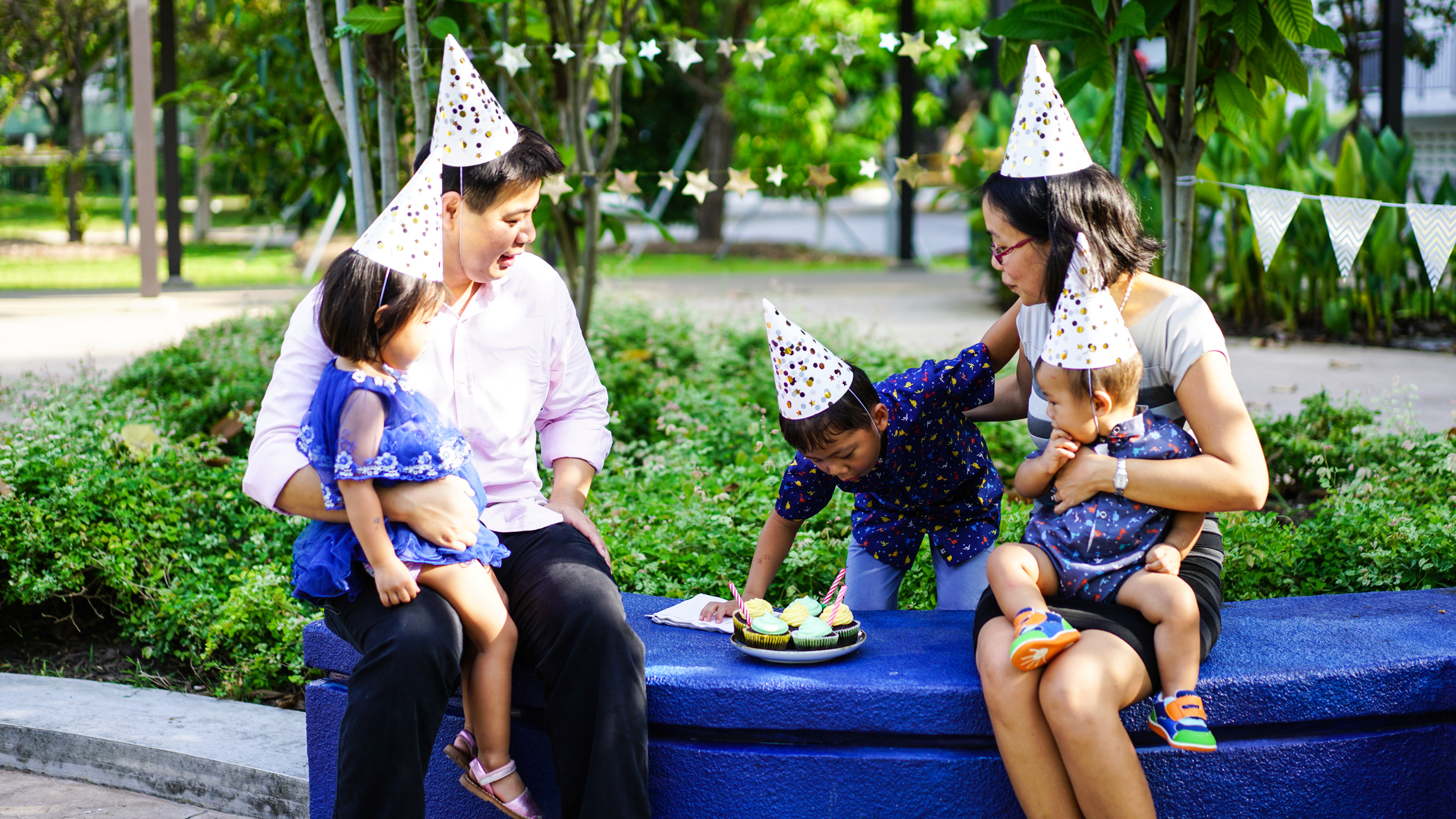 Family in party hats celebrating on public bench