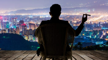 Man in chair with cigar, looking down on 20+ commercial properties