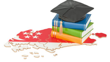 Graduation cap on top of books and a Singapore map