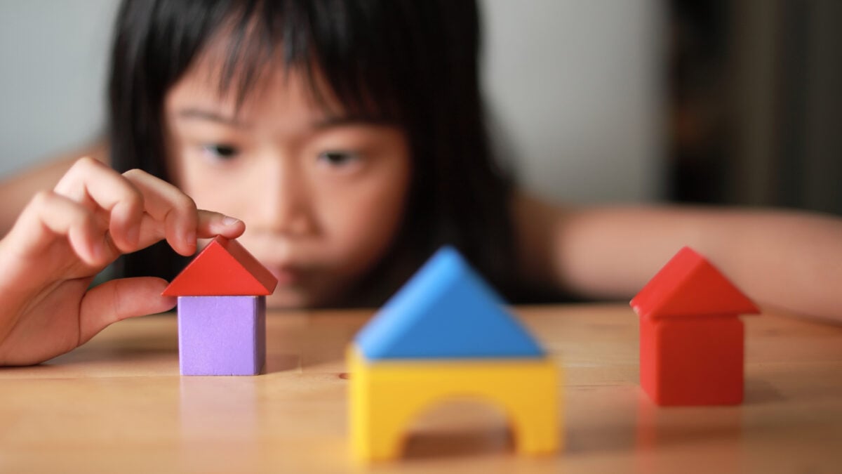 A child building houses with play blocks
