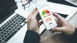 Person looking at his phone with an image of a credit score graph