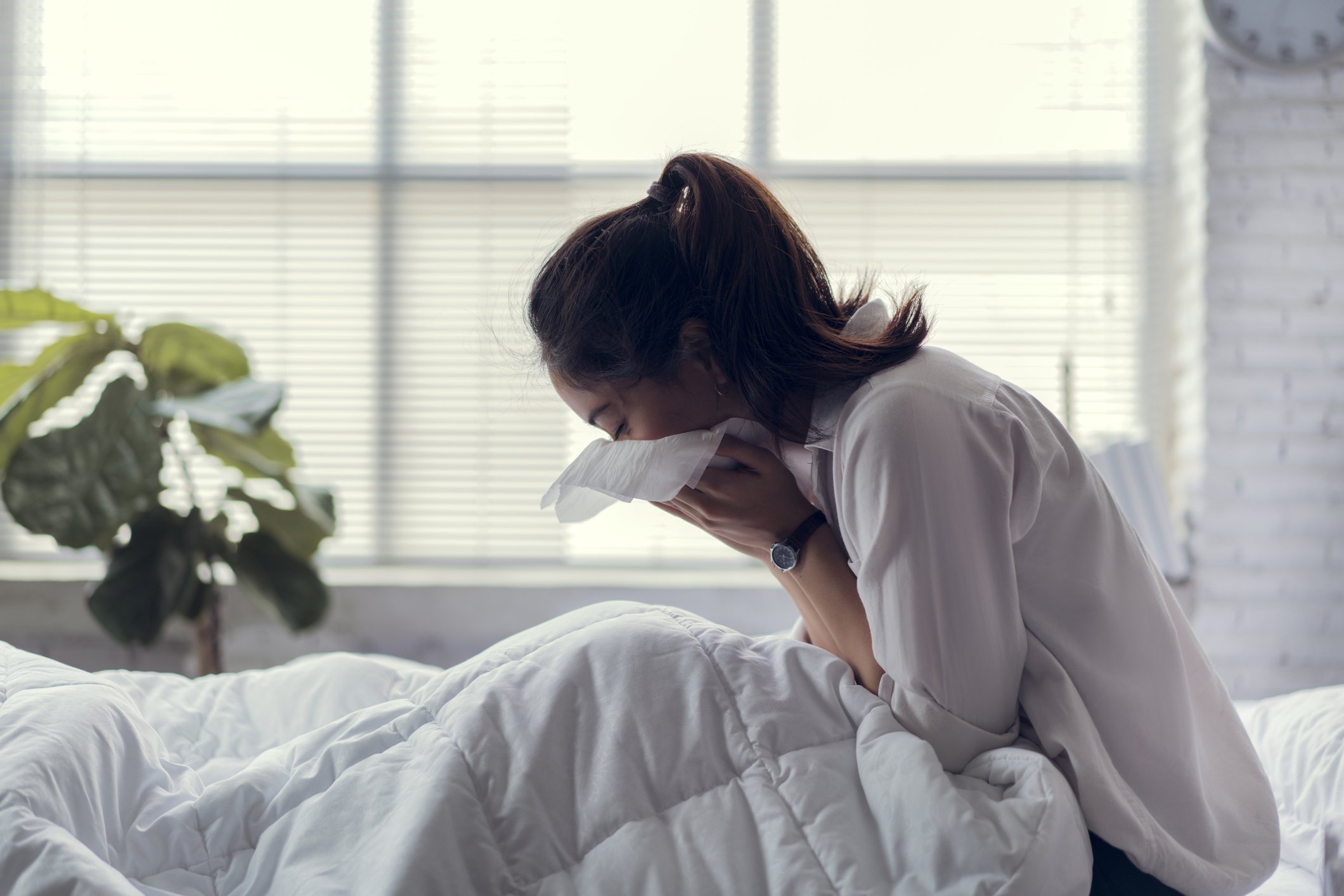 Sneezing lady sitting up in bed