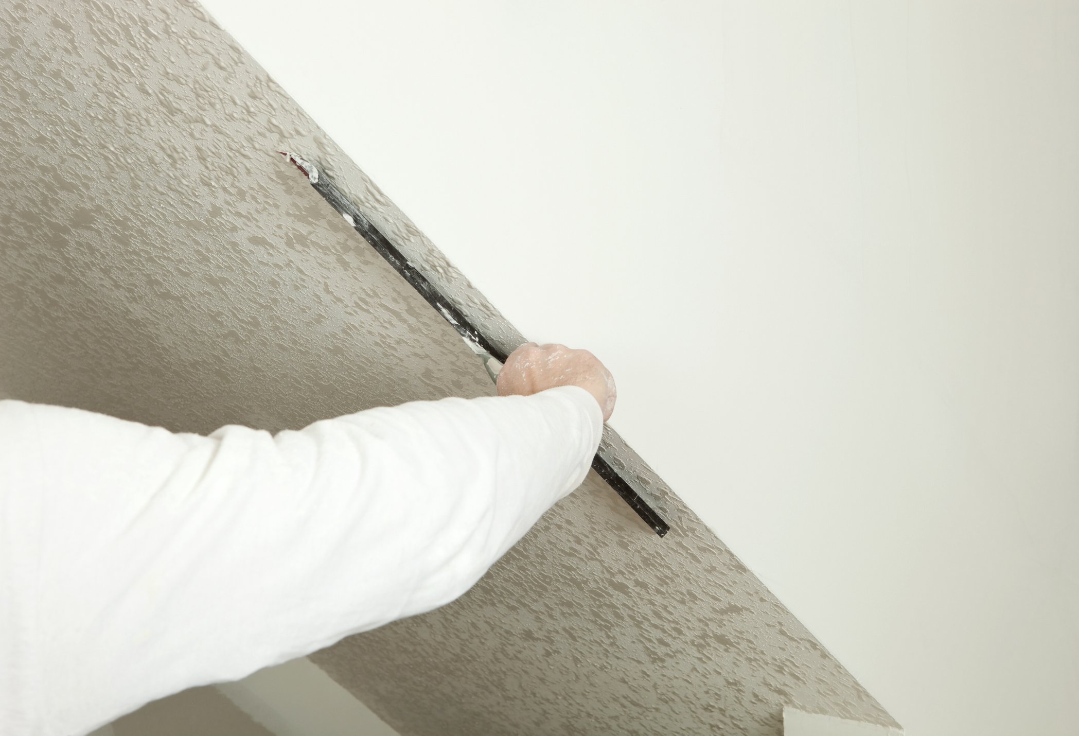 Scraping off a popcorn ceiling with a trowel