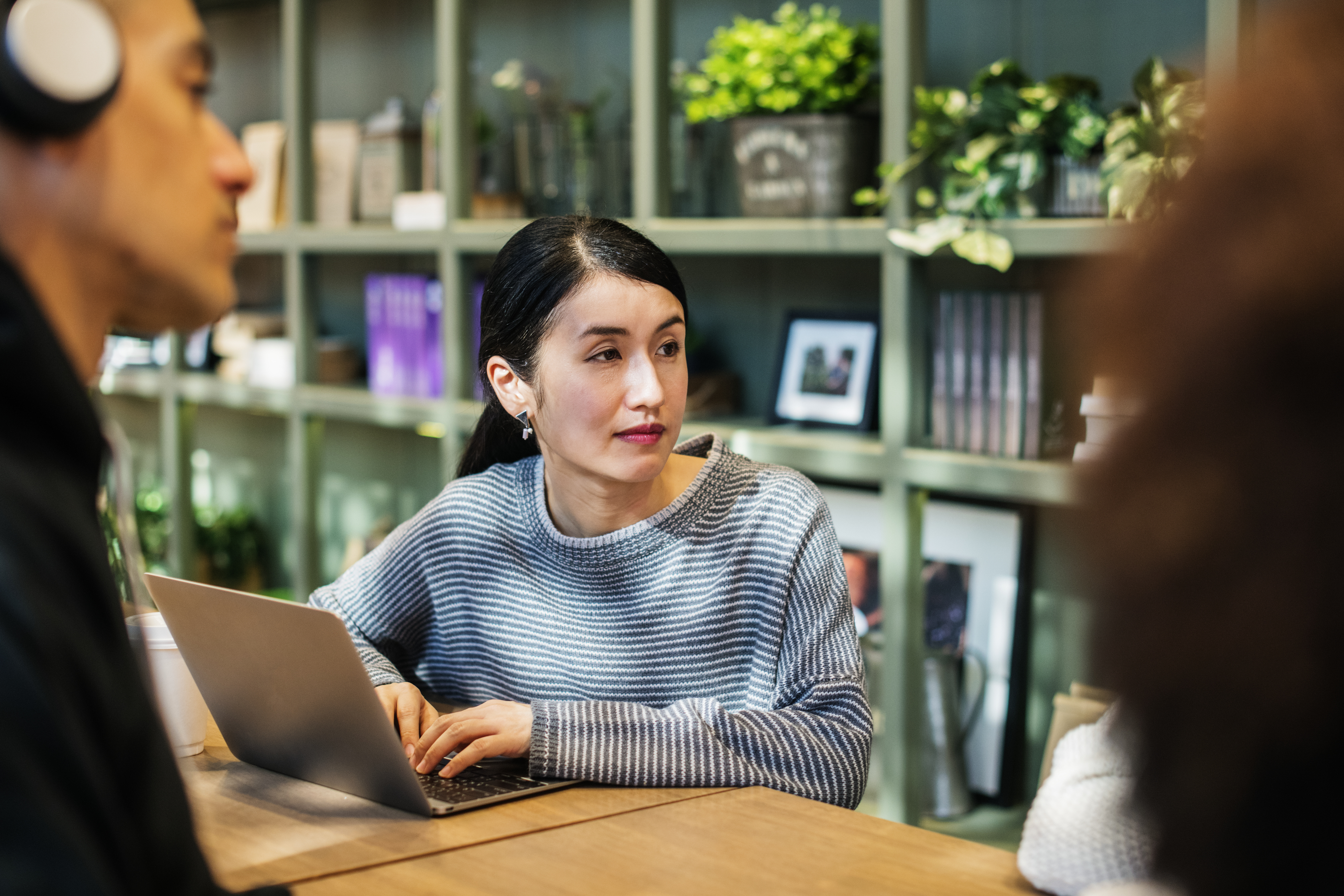 Asian woman with laptop talking to others