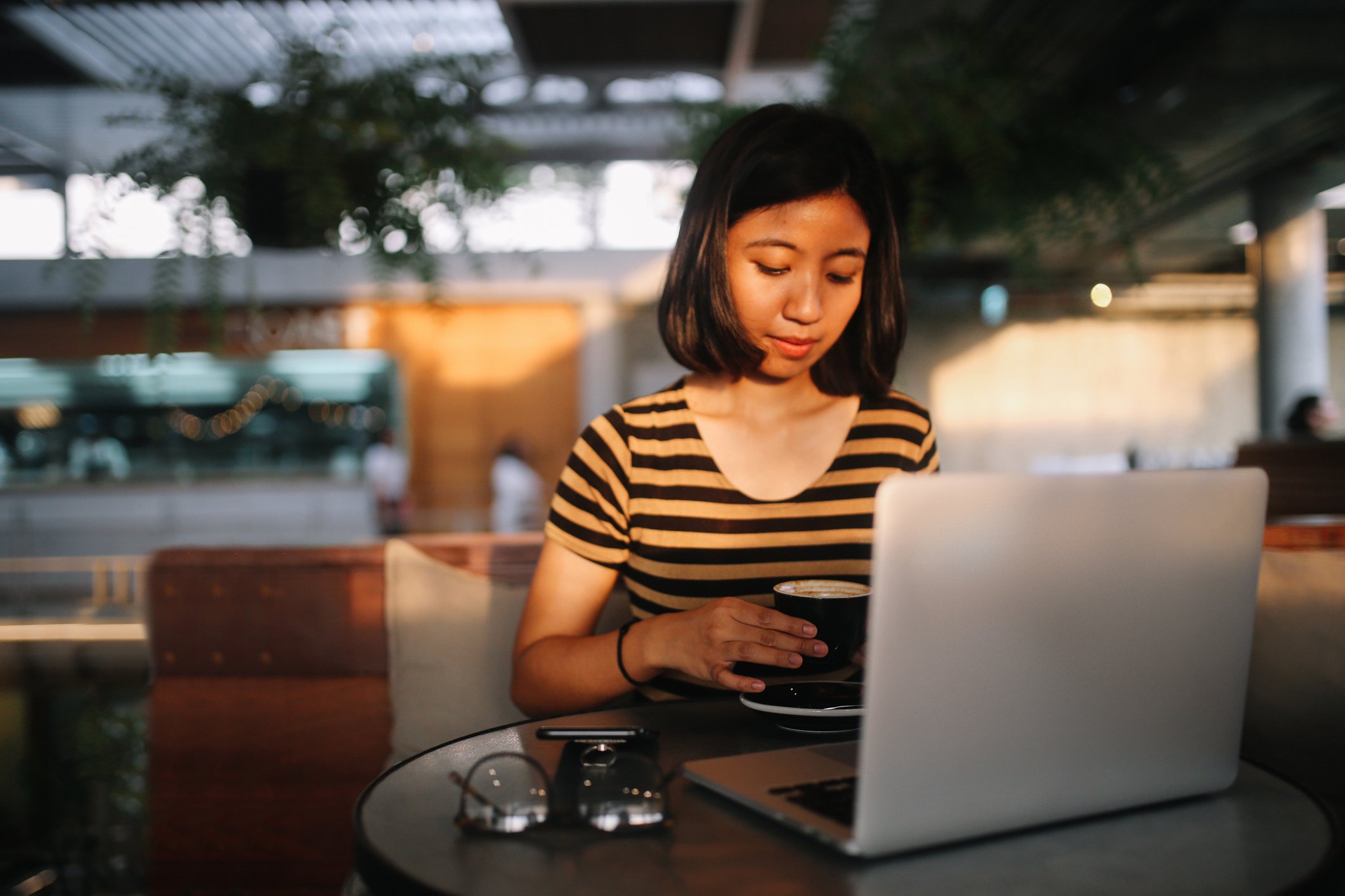 Young Asian freelancer working on the laptop while having a coffee