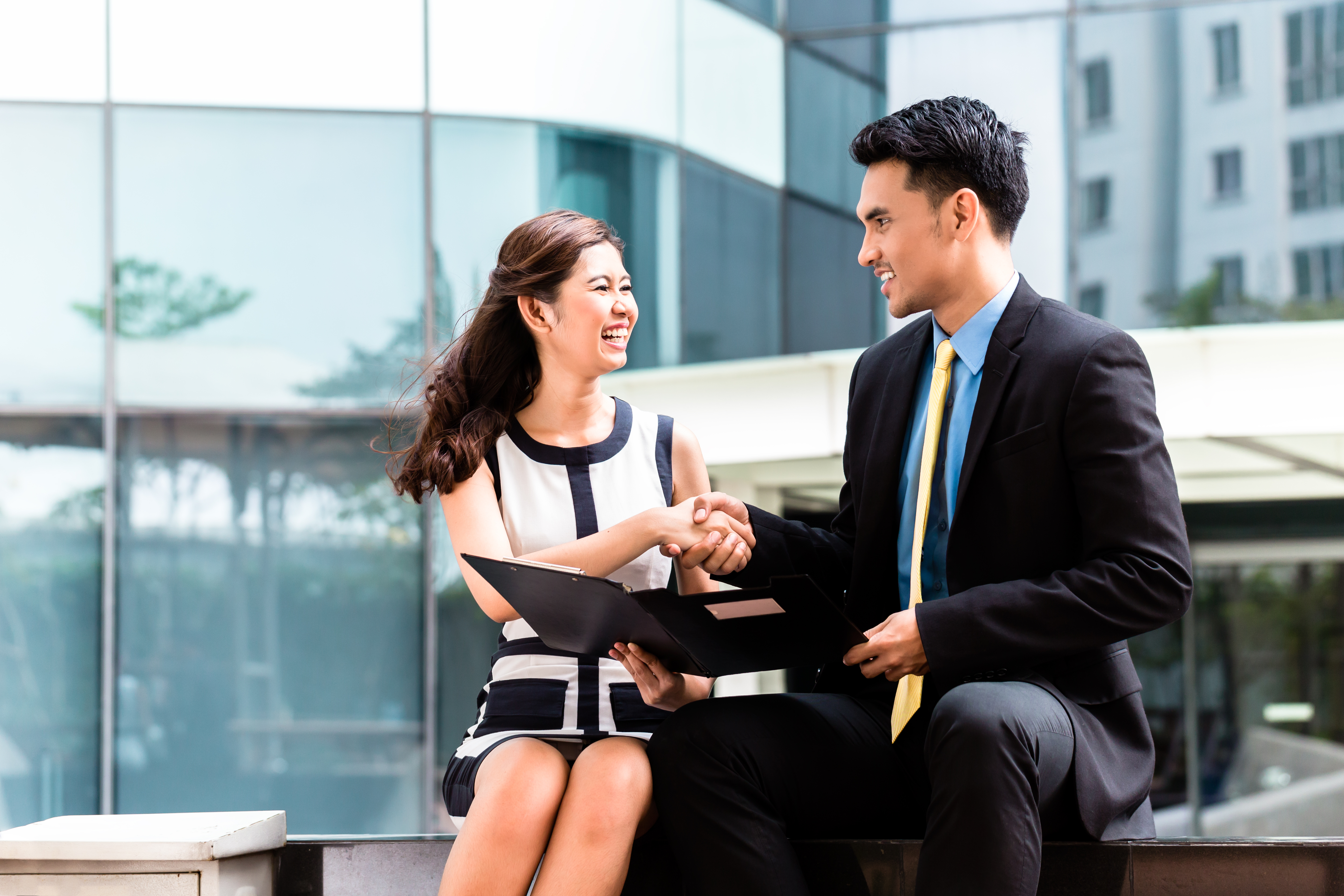 Man and woman shaking hands while looking at a document