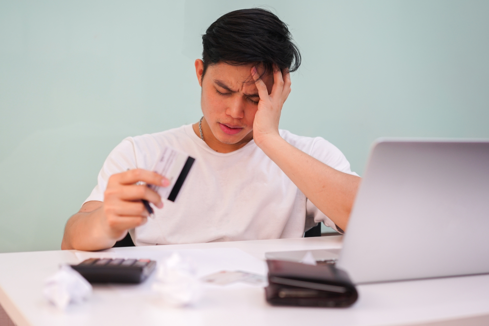 Young man getting a headache after calculating his payments