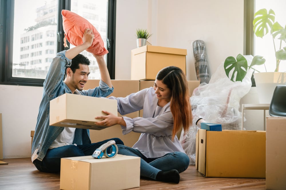 Asian couple play fighting inside their new home