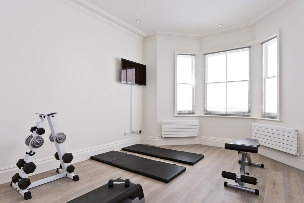 Home gym with equipment such as yoga mat, weights rack and bench