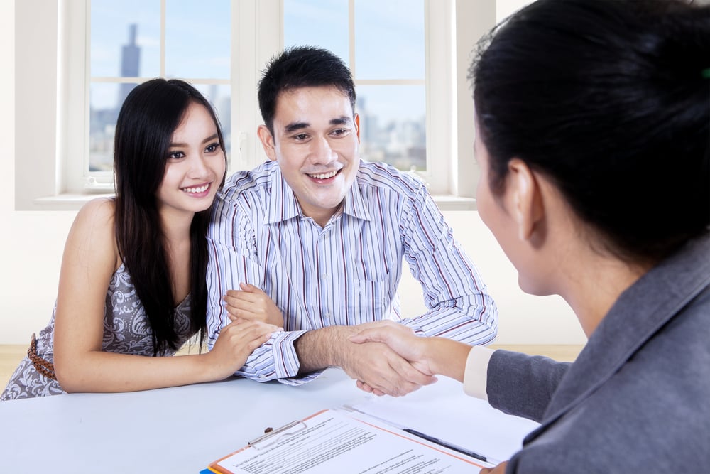 An asian couple signing up for home renovation loan. 