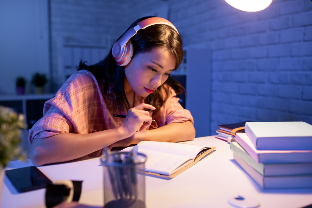 A girl enjoying her music while studying.