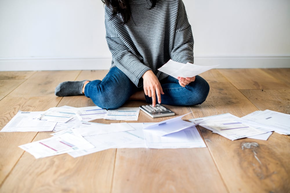 girl calculating expenses with calculator on the floor