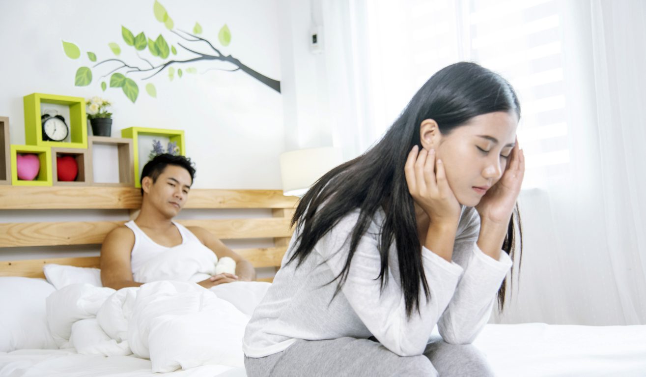 woman and man sitting on a bed stressed