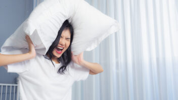 Woman covering ears with a pillow