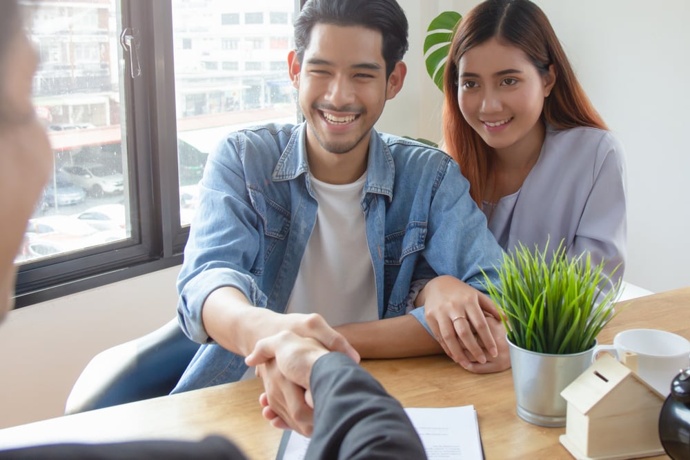 A couple shaking hands after signing mortgage