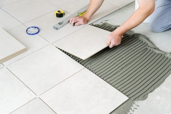 A contractor laying tiles on the cement screed