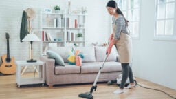 A woman vacuuming living room to allergy-proof home