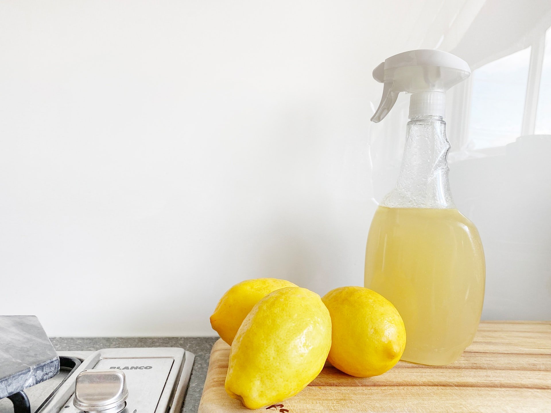 Three lemons and a spay bottle containing a mixture of vinegar and lemon, which can help get rid of ants and termites