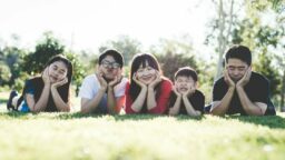 A family of five lying on grass