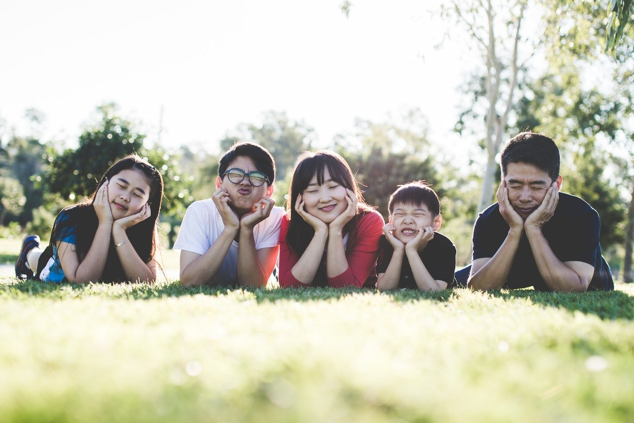 A family of five lying on grass