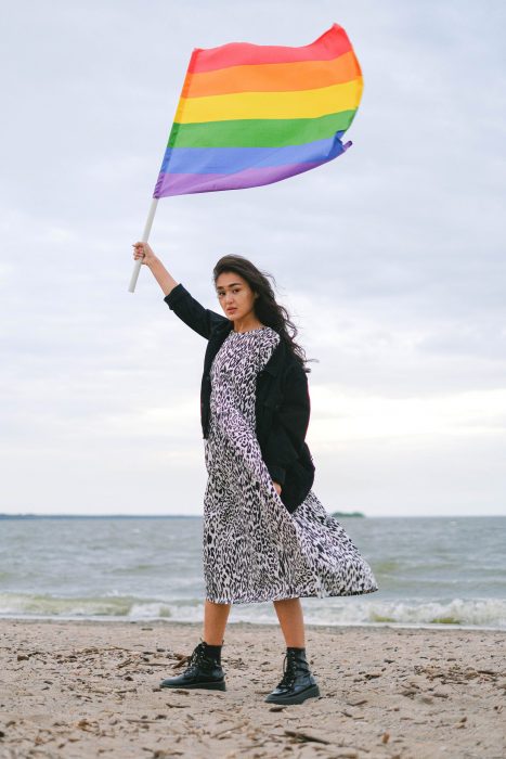 asian woman holding pride flag on beach