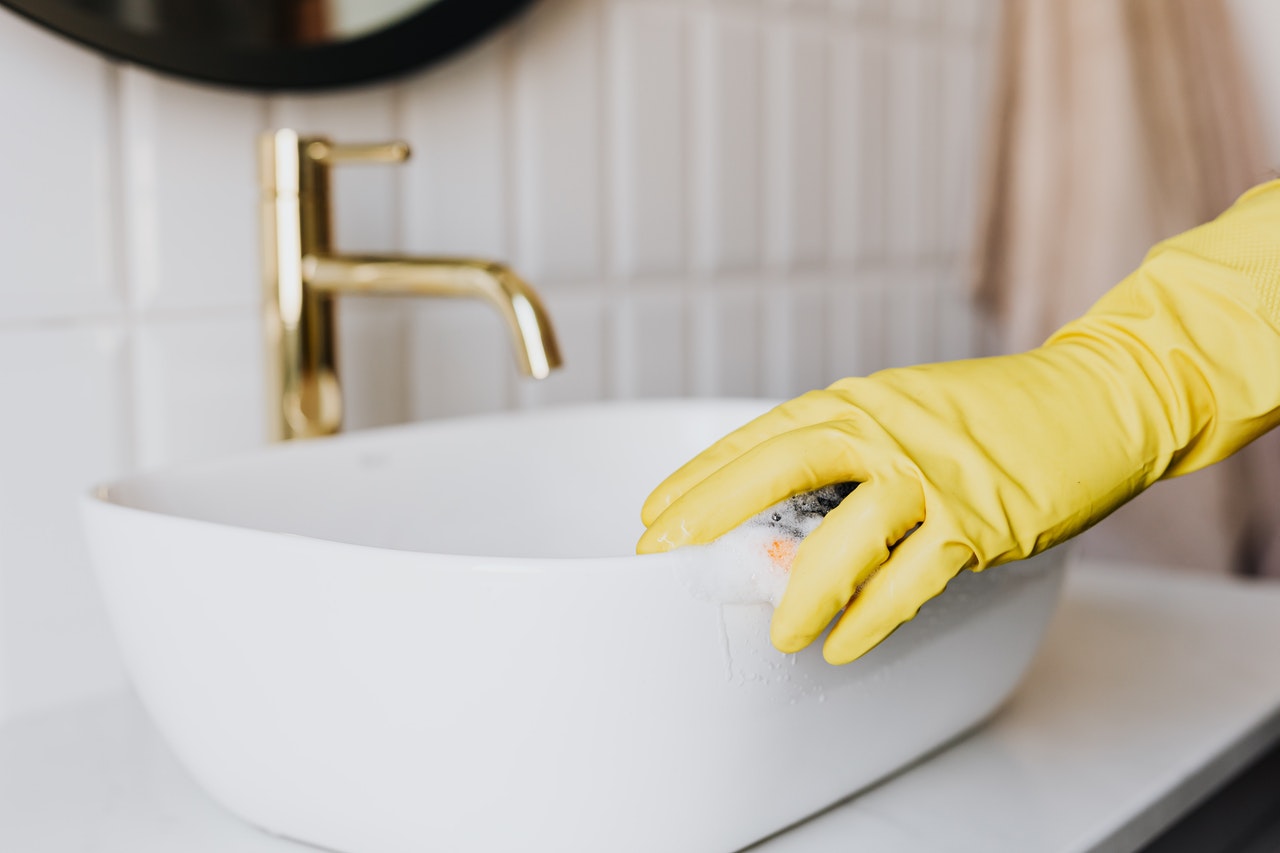 Person wiping toilet sink