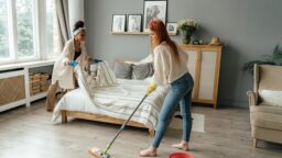 Middle age LGBTQ gay female caucasian couple cleaning bedroom