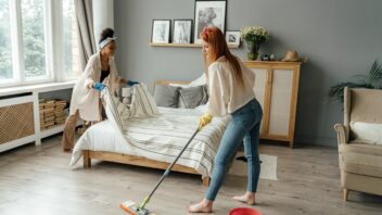 Middle age LGBTQ gay female caucasian couple cleaning bedroom