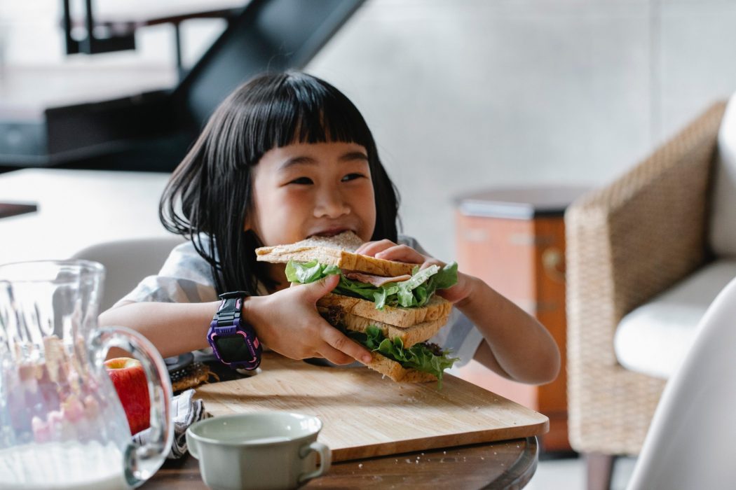 asian girl eating sandwich bread