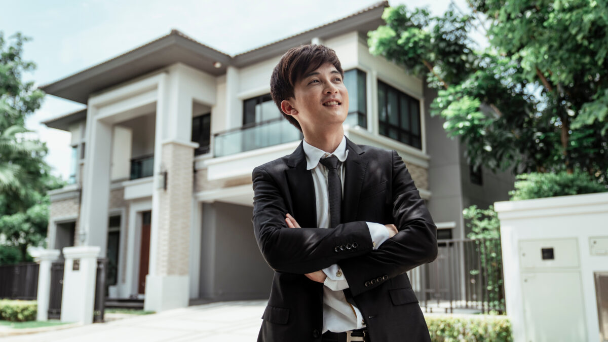 Successful privileged young Asian man in front of bungalow