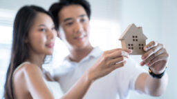couple holding wooden house