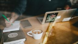 A person working on their laptop with a cup of coffee next to them