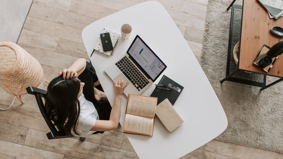 A person sitting at a desk with a computer and books