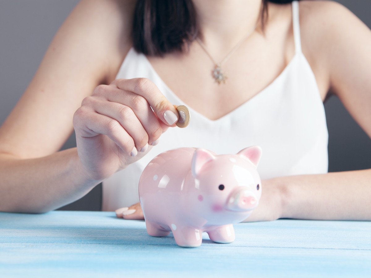 A lady putting coins into a piggy bank