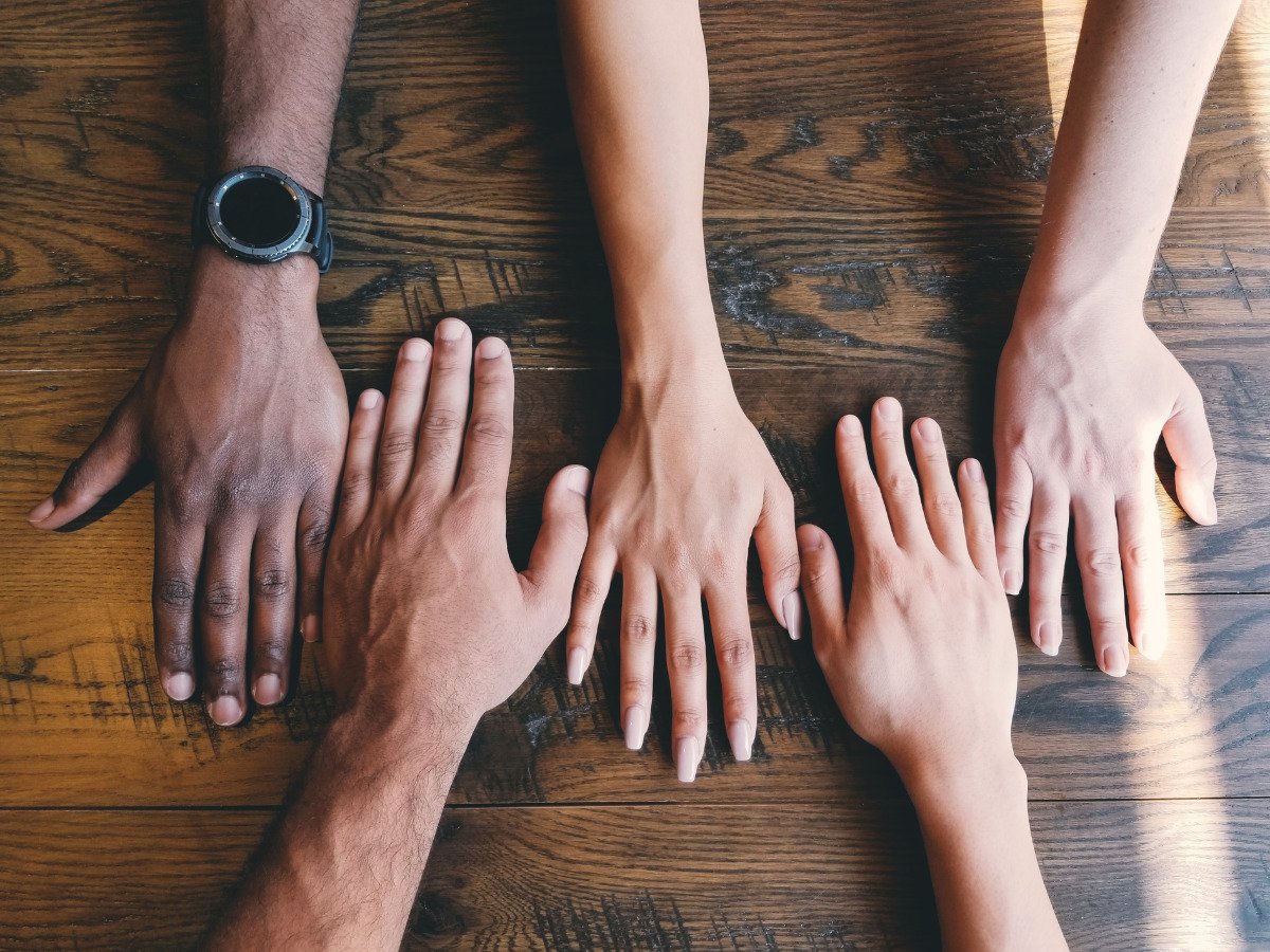 different skin tone hands on a table - President Tharman