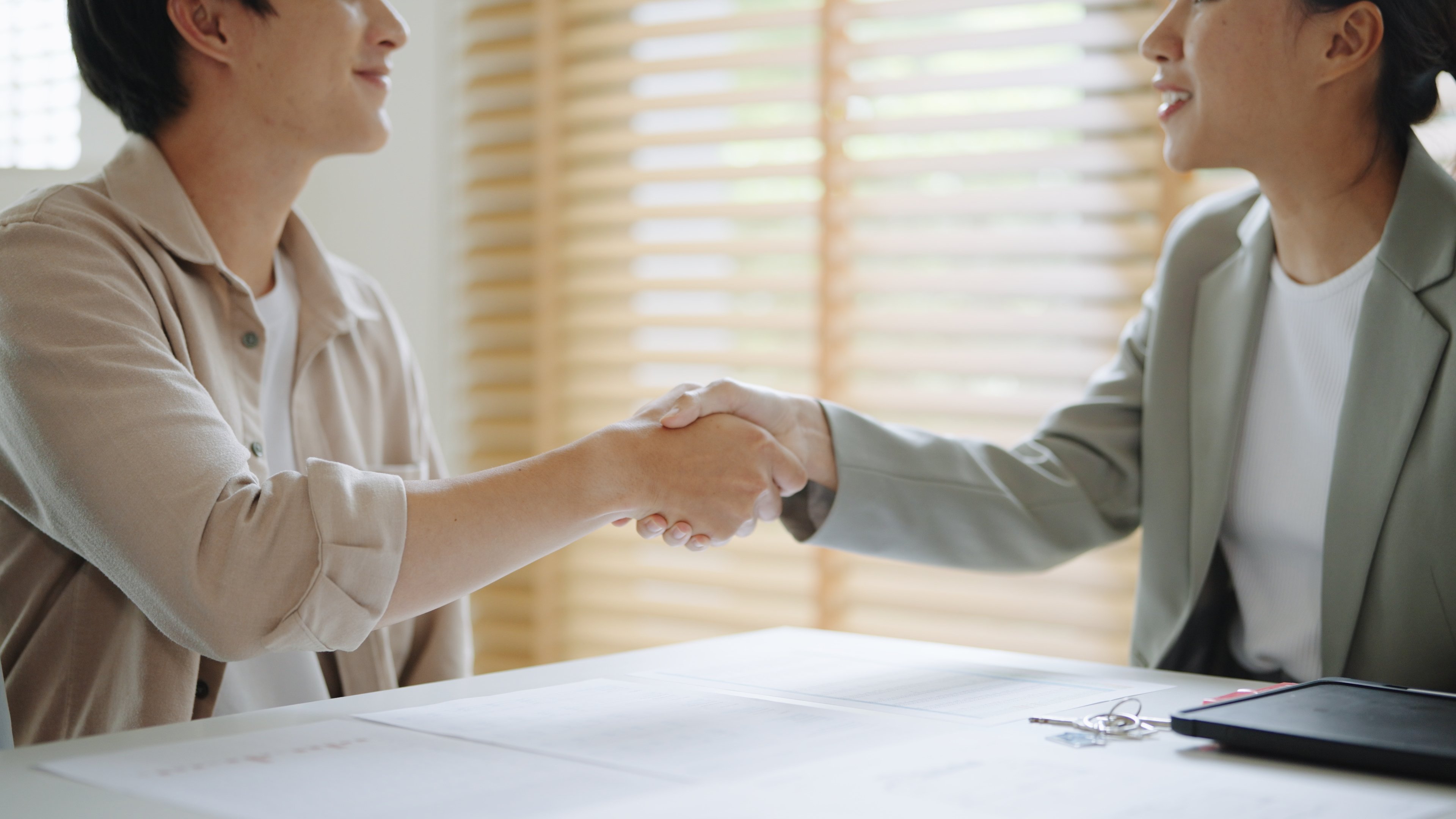 Young asian couples shaking hands with female real estate agent business deal agreement buy a new house successful - pros and cons of buying second property singapore