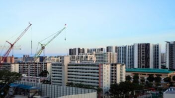 Construction site with two tall construction cranes building new housing development in Dakota, a residential neighbourhood in the east of Singapore