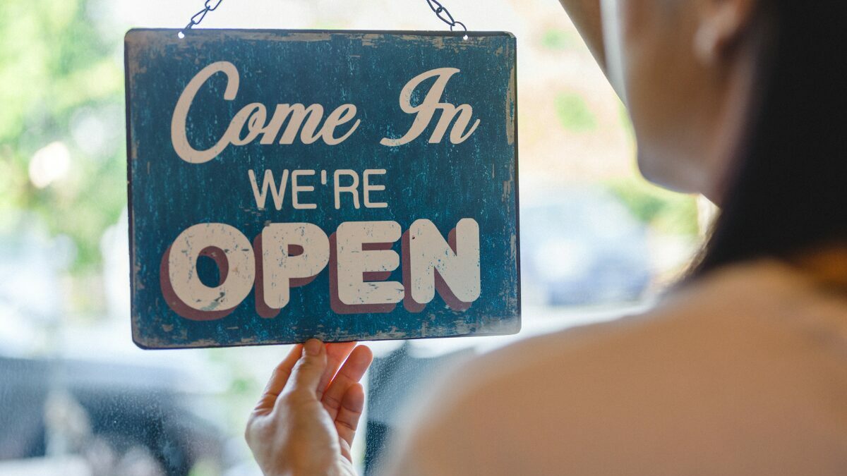 Happy Asian business owner hanging an open sign on the cafe door