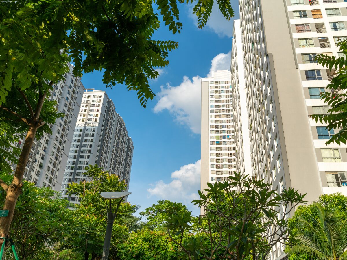 Modern condominium building with green leaves on foreground